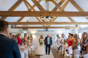 Bride is escorted by her father at Cottesmore Golf Club
