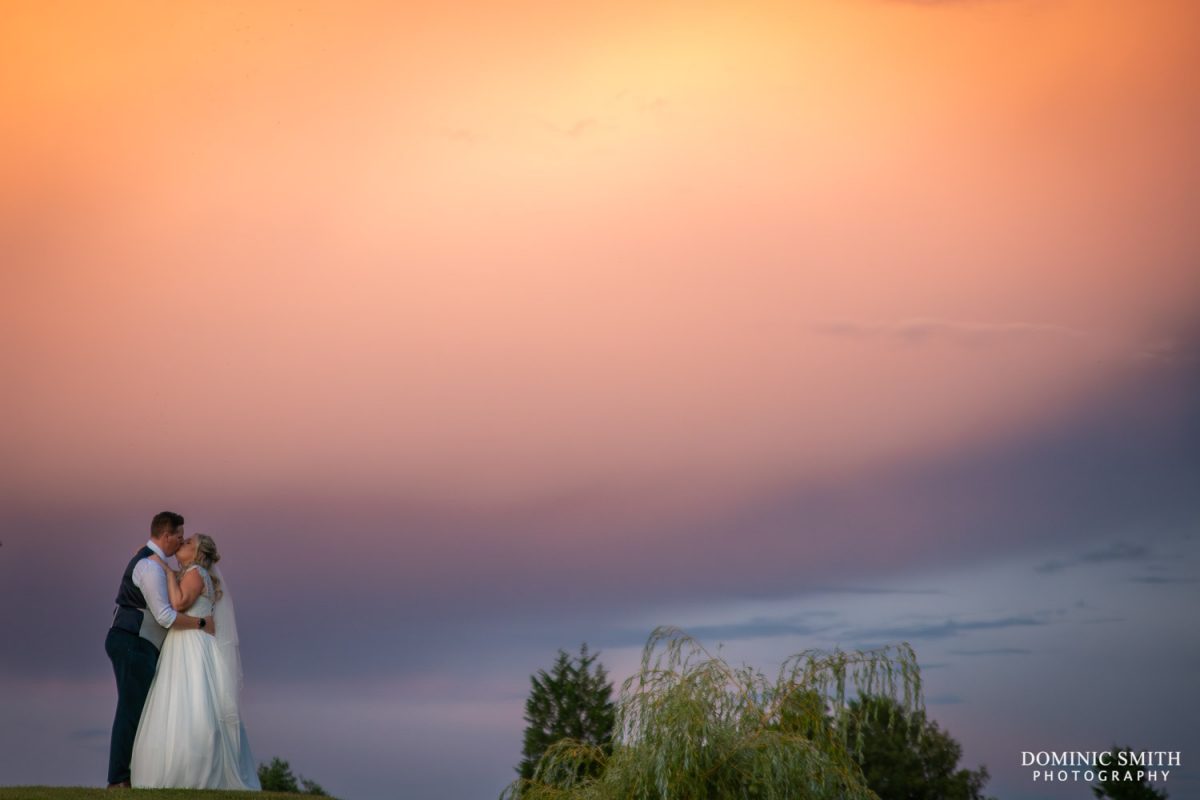 A sunlit storm cloud creates a dramatic background for a bride and groom at Cottesmore Golf Club