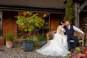 Bride and Groom sitting on a bench at Cottesmore Golf Club