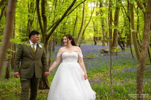Bride and Groom walking through the bluebells at Gildings Barns
